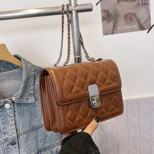 Detail of a brown quilted leather crossbody bag with silver chain strap and metal lock
