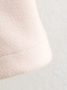 Detailed close-up of the smooth hem stitching on this beige wool-textured jacket