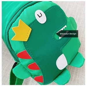 Close-up of cute green dinosaur pattern with yellow crown on kids chest bag