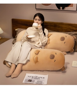 Detail of soft capybara long plush pillow featuring embroidered eyes on a cozy bed