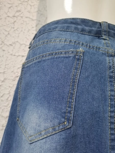 Detail of washed blue denim skirt featuring yellow contrast stitching and back pocket