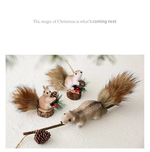 Detailed view of plush squirrel Christmas ornaments with pine cones on snowy ground