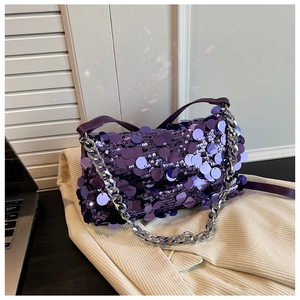 Detailed view of luxury purple sequin handbag with thick silver chain on a beige surface