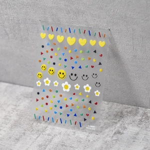 Gros plan de stickers à ongles 3D en relief avec sourires colorés et petites marguerites