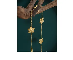 Detailed close-up of gold-plated daisy charms with hammered texture on a long necklace chain