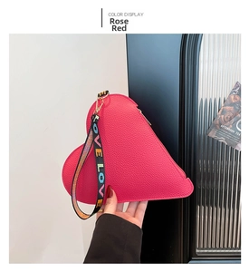Gros plan du sac cœur rose rouge texturé avec dragonne LOVE pour un look tendance