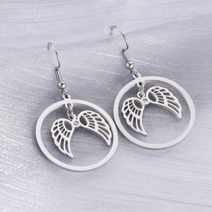 Macro view of silver angel wing earrings with a small central crystal on gray fabric