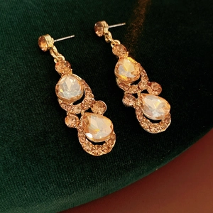 Détail de boucles d'oreilles vintage dorées avec cristaux ambrés sur velours vert