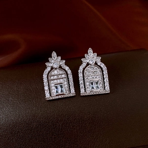Macro shot of silver zircon hollow earrings featuring arch design on leather texture