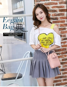 Close-up of pink mini PU leather handbag featuring matte finish and top handle on brick wall