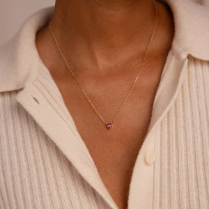 Close-up of 18K gold-plated heart-shaped red stone necklace on a model's neck