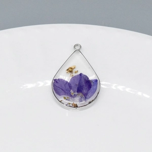Detailed view of teardrop resin pendant with purple dried flower and gold foil flakes