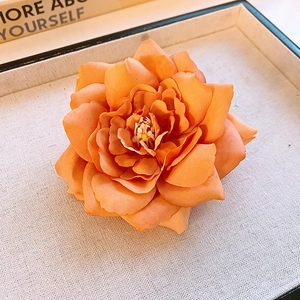 Elegant orange orchid fabric hair claw clip presented in a beige linen jewelry box