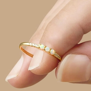 Detailansicht eines Goldrings mit drei runden weißen Opalen und seitlichen Zirkonia