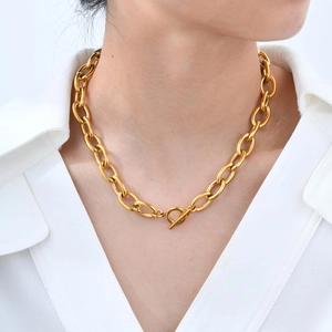 Detail of chunky gold chain necklace with toggle clasp on white shirt model