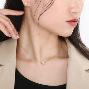 Close-up of a model wearing a gold paw print jewelry set with sparkling white stones