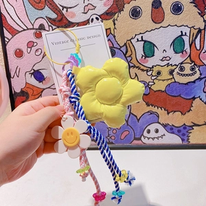 Détail d'un porte-clés tressé coloré avec une grande fleur jaune et un petit smiley blanc