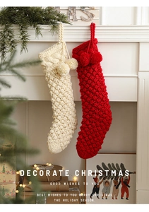 Detail of red and cream cable knit Christmas stockings with pom poms on a fireplace