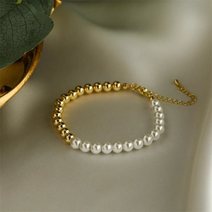 Detail of adjustable pearl and gold bead bracelet with lobster clasp on grey silk fabric