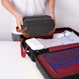 Men's vintage canvas and PU leather toiletry bag shown being packed into a suitcase.