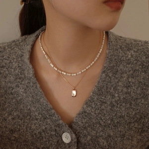 Close-up of a double-layered S925 silver necklace with mother-of-pearl pendant on a model