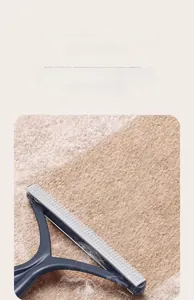 Close-up of a blue manual pet hair remover showing the gray non-slip scraper on carpet