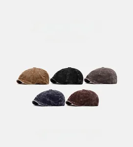 Five assorted colors of corduroy newsboy caps displayed on a clean grey background