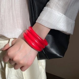 Close-up of a three-piece bold red resin geometric bangle set worn by a fashion model