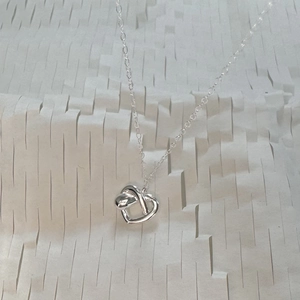 Macro shot of 925 sterling silver interlocking heart pendant on white honeycomb paper