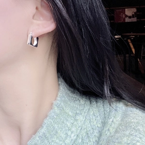 Close-up of square geometric silver earrings worn by a model in a minimalist style