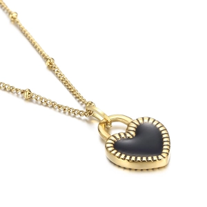 Macro shot of gold heart pendant necklace with black inlay and radial textured edges