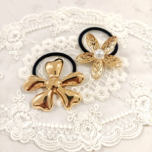 Golden starfish floral hair ties with pearl detail on elegant white lace background