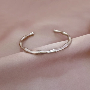 Macro shot of silver bamboo textured stainless steel cuff bracelet on silk fabric