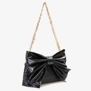 Detail view of black faux leather handbag featuring crocodile texture and bow decoration