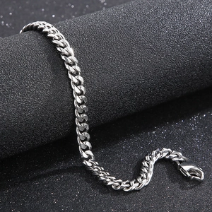 Macro shot of silver Cuban link chain bracelet with polished finish on black background