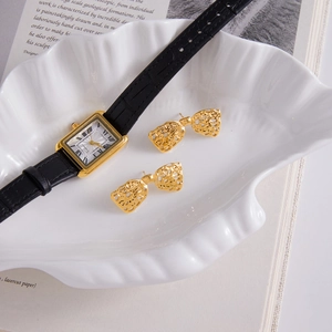 Élégantes boucles d'oreilles nœud dorées et coffret montre classique sur plateau en coquillage