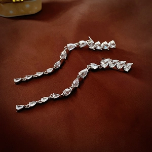 Detail shot of elegant silver teardrop zircon tassel earrings on dark velvet