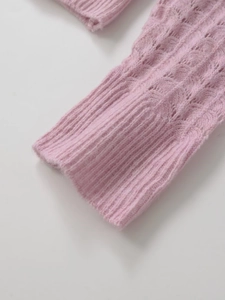 Detail of pink knit sweater cuff showing wave texture and ribbed wrist design