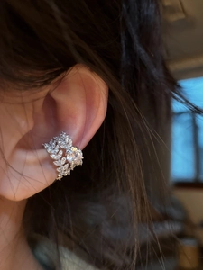 Detailed close-up of a silver zircon ear cuff featuring leaf patterns on woman's ear