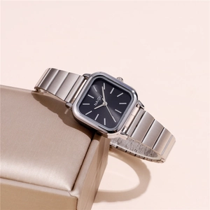 Detail of square silver steel watch with black dial on a golden satin display box