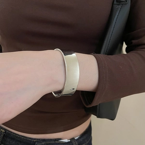 Gros plan d'un large bracelet manchette argenté minimaliste porté avec une tenue décontractée