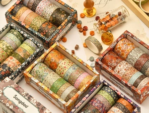Close-up of assorted floral washi tape rolls in vintage boxes with decorative stationery