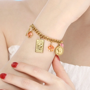 Close-up of a vintage gold chain bracelet featuring a queen coin pendant and crystal beads