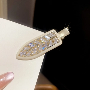 Macro shot of cubic zirconia arrow hair clip featuring a cream border and sparkling rhinestones