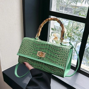Detail of green crocodile texture handbag with luxury bamboo handle and gold hardware