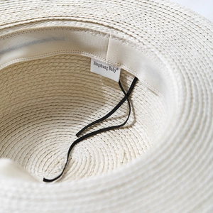 Detail of straw sun hat interior with wide fabric sweatband and elastic chin strap