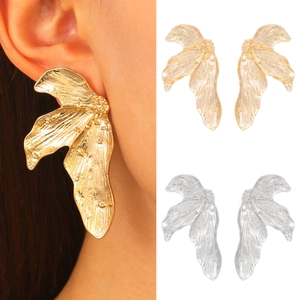 Exaggerated gold and silver leaf earrings with irregular hammer texture on model
