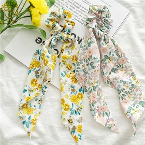 Detailed view of floral chiffon scrunchies with long ribbons in pink and yellow floral prints