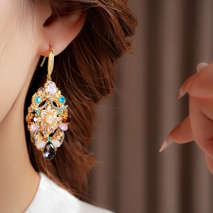 Close-up of vintage gold drop earrings with colorful crystals worn by a model