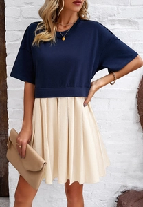 Dettaglio di un abito bicolore con top blu scuro a maniche corte e gonna a pieghe beige